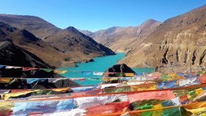 Türkisblauer Stausee mit tibetischen Gebetsfahnen